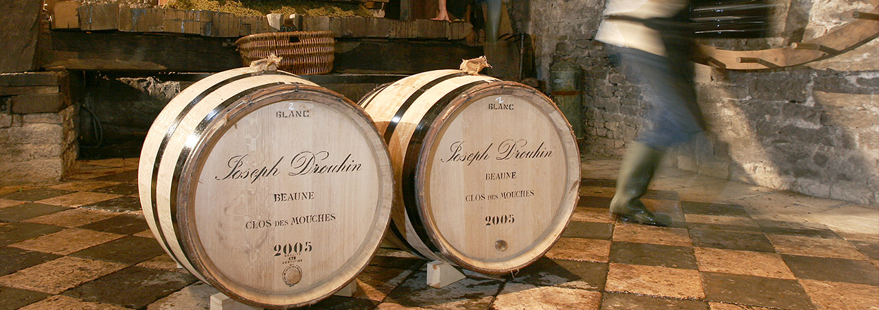 Holzfässer im Weinkeller des burgunder Weingut Joseph Drouhin, im Hintergrund Mitarbeiter vom Domaine