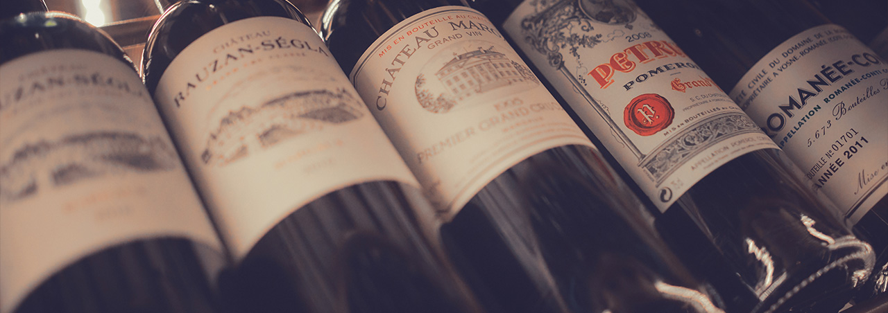 Stimmungsvolle Nahaufnahme großer Rotweine, Château Margaux 1995, Rauzan-Sécla, Pétrus, zusammen mit anderen Weinen in einem Weinregal in einem Restaurant. 