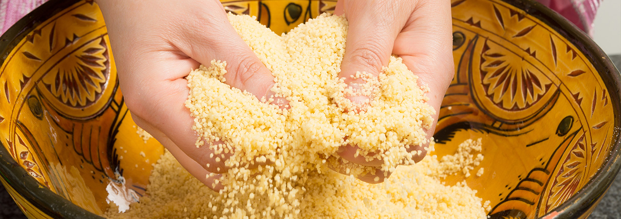 Une image d'une personne disposant dans ses mains de semoule de couscous. 