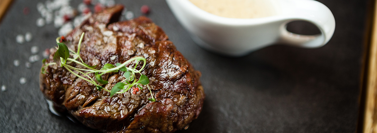 Une photo d'un filet mignon sur une ardoise accompagné d'une sauce à la crème. 