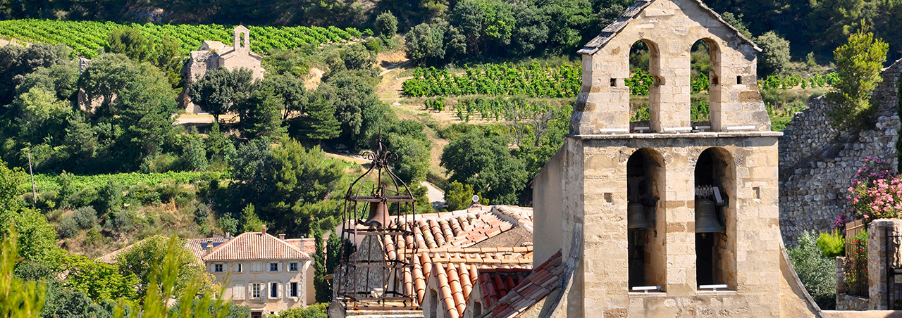 Idyllische Aufnahme von Weinbergen im Weinbaugebiet Gigondas in Südfrankreich, im Vordergrund eine historische Kirche