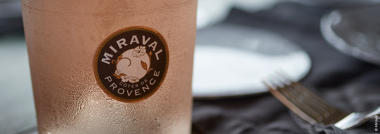 Nahaufnahme der charakteristischen, frisch gekühlten Miraval Rosé-Flasche, Fokus auf das runde Etikett
