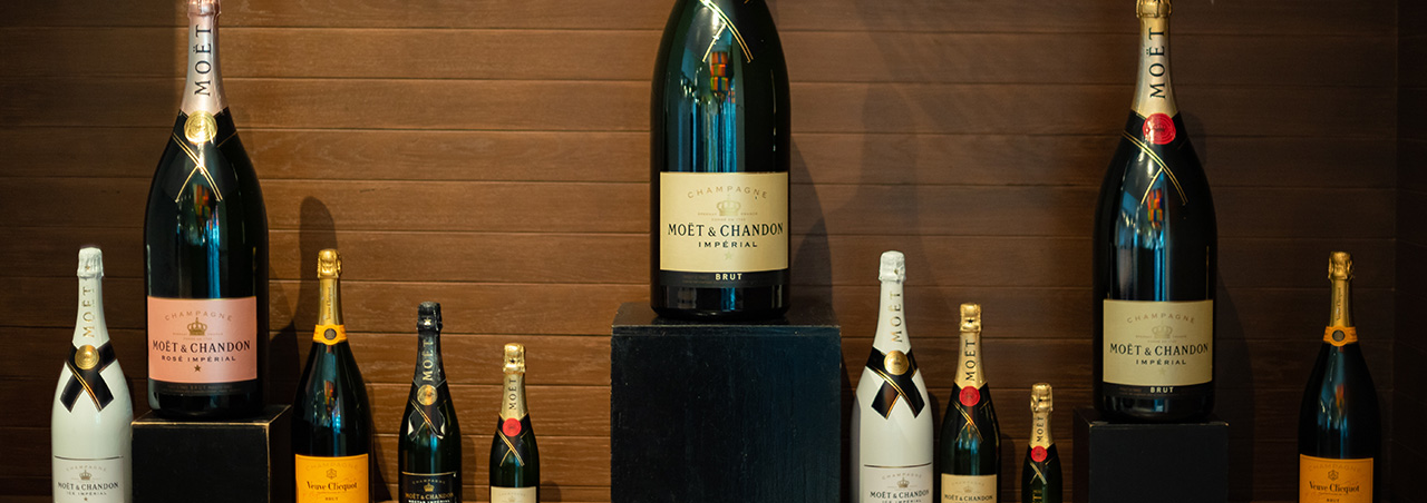 Verschiedene Moët & Chandon Flaschen, darunter Übergrößen und Halb-Flaschen, nebeneinander aufgereiht