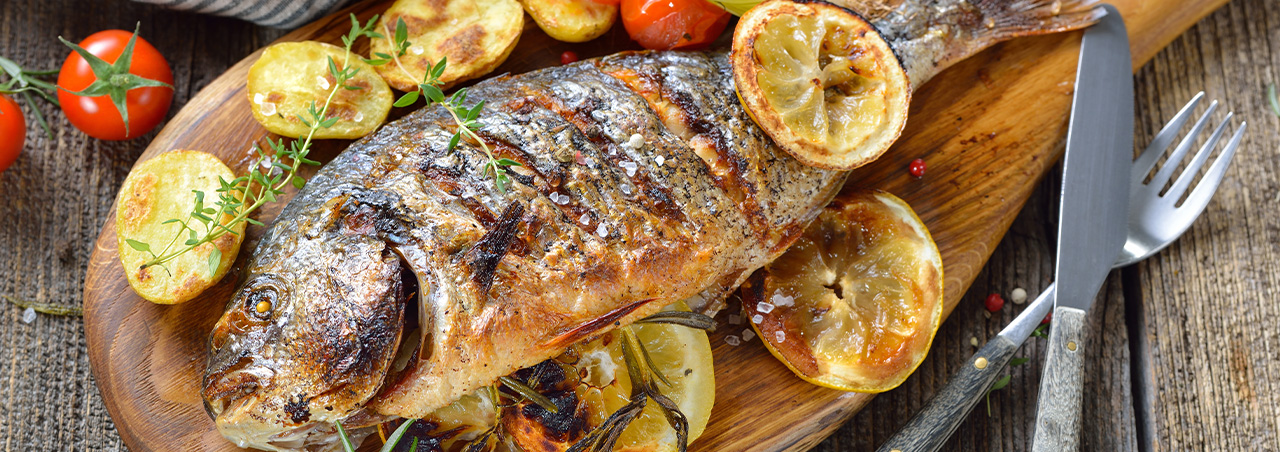 Fisch vom Grill mit Gemüse und Zitronenscheibe