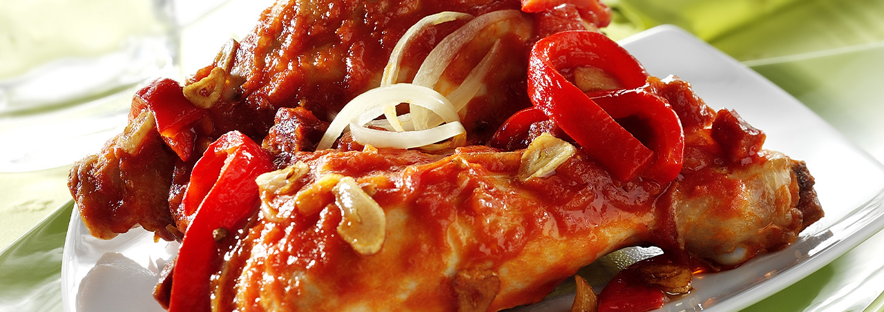 Une photographie d'assiette mettant en valeur une portion de poulet basquaise.