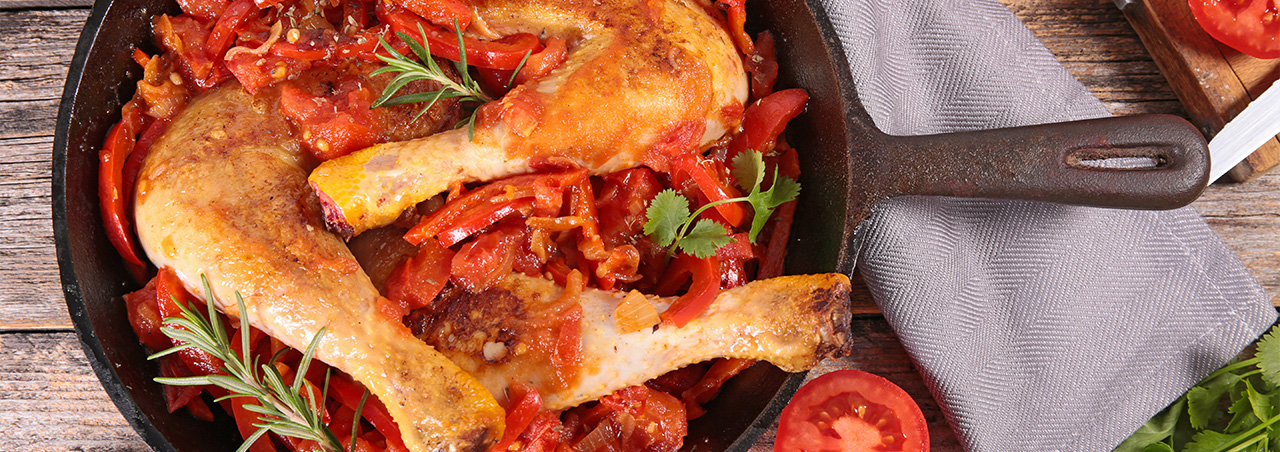 Une photographie d'un plat de poulet basquaise, mettant en avant une piperade savoureuse et un poulet rôti dressés harmonieusement dans un même plat.