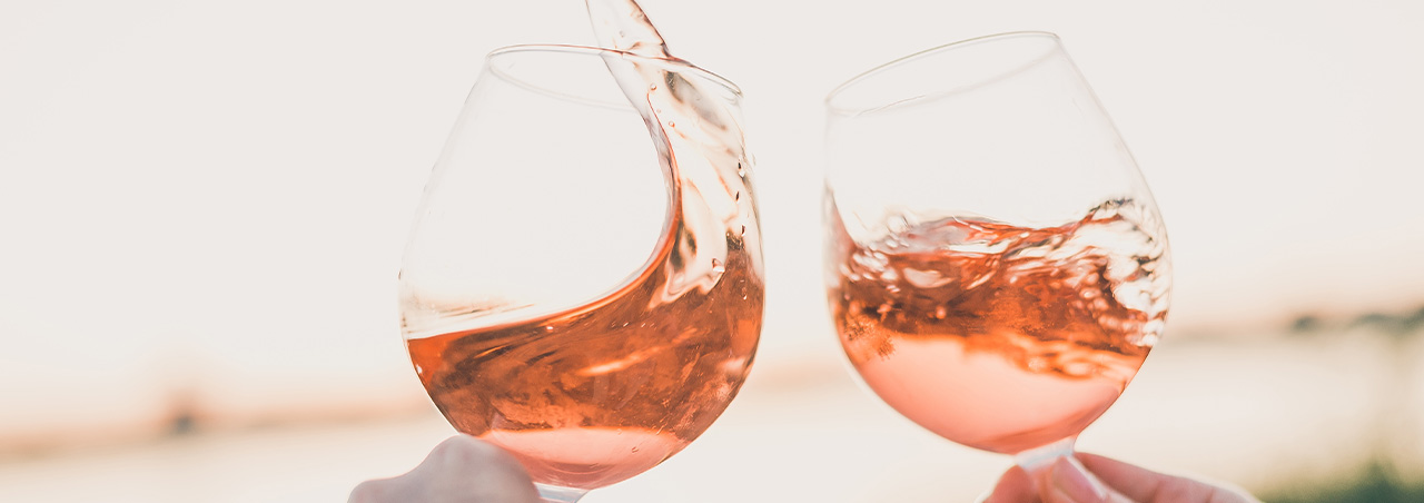 Zwei Frauenhände stossen mit Roséwein an