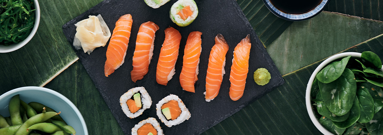 Sushi Nigiri Lachs und Maki Rolls, präsentiert auf scharzer Schiefertafel