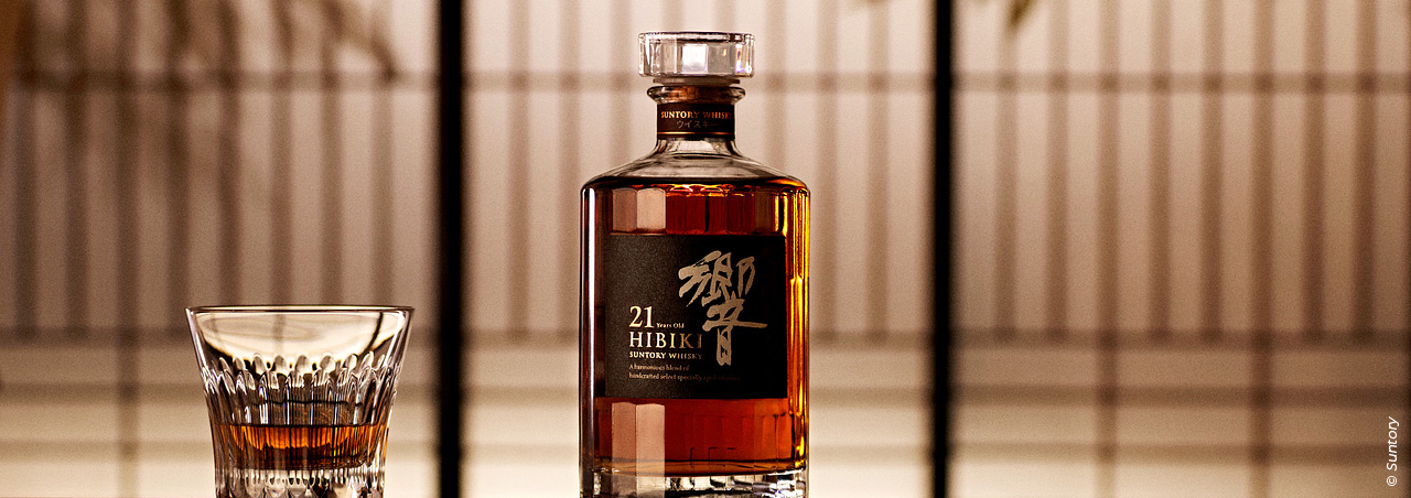 Bouteille de whisky Suntory accompagnée d'un verre dans un décor raffiné.
