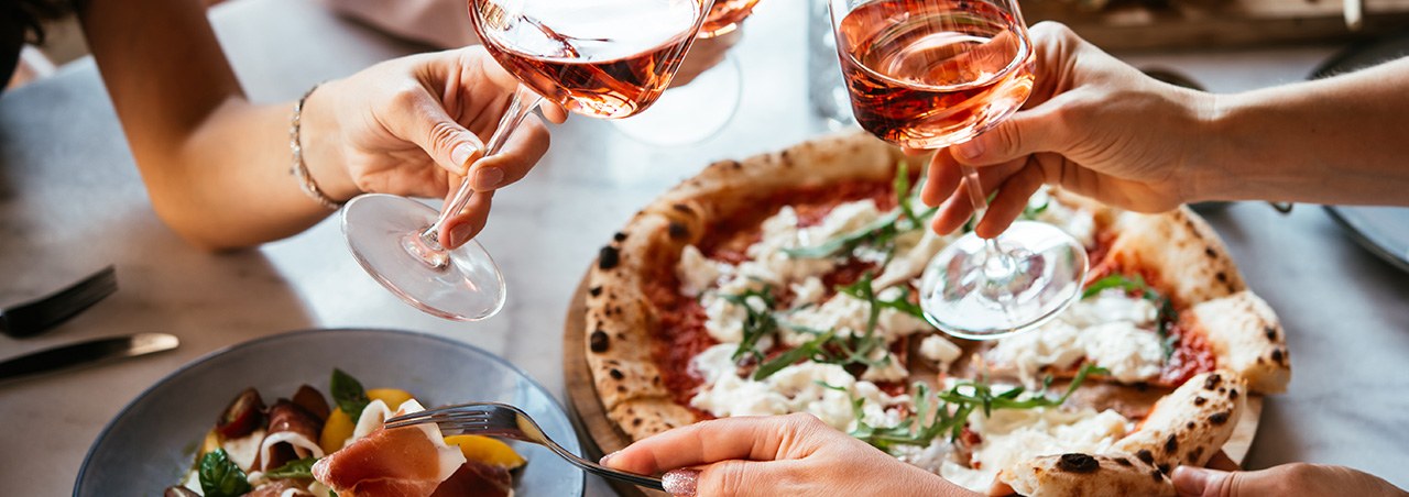 Freunde genießen eine Dinnerparty mit Pizza und Roséwein in einer Bar oder einem Restaurant