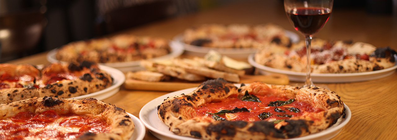 Frische neapolitanische Pizza und ein Glas Rotwein auf Holztisch