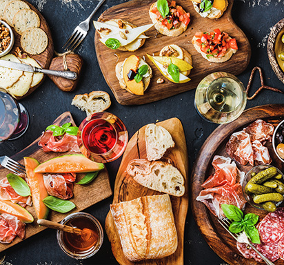 Ansprechende Antipasti, Vorspeisen und Weine auf einer dunklen Tischplatte