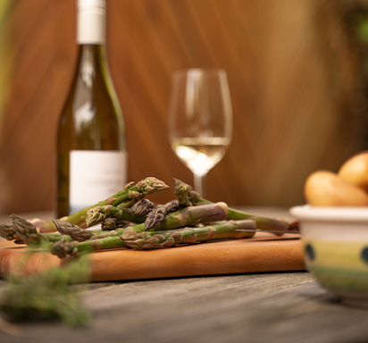 Gründer Spargel, daneben Kartoffeln, eine Flasche Wein und ein gefülltes Weinglas