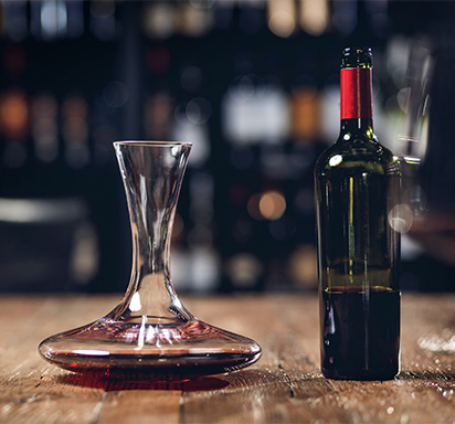 Dekanter mit Rotwein-Flasche auf Holztisch