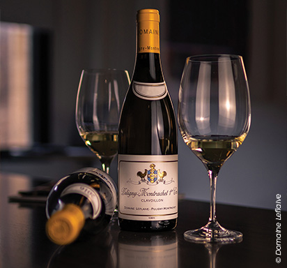 Eine elegante Fotografie, die eine Flasche Puligny-Montrachet Premier Cru des renommierten Domaine Leflaive in den Mittelpunkt rückt und durch ein sanftes Licht veredelt wird.