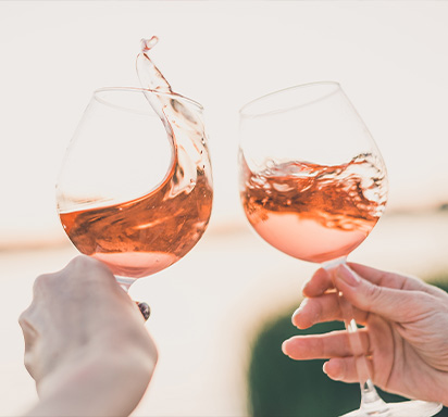 Zwei Frauenhände stossen mit Roséwein an