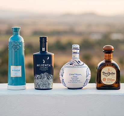 Une photographie mettant en scène quatre flacons de tequila de prestige, issus des maisons Don Julio, Grand Mayan, Komos et Mijenta.