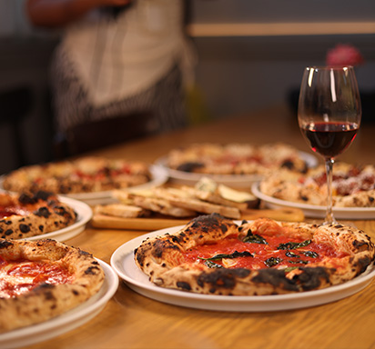 Frische neapolitanische Pizza und ein Glas Rotwein auf Holztisch 