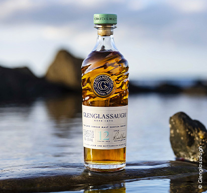 Une photographie d'un whisky de la maison Glenglassaugh, mis en scène en bord de mer.
