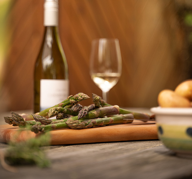 Gründer Spargel, daneben Kartoffeln, eine Flasche Wein und ein gefülltes Weinglas