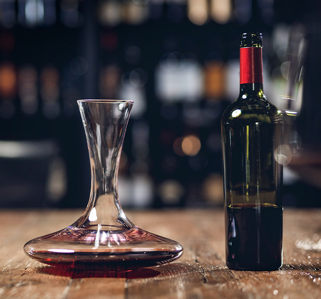 Dekanter mit Rotwein-Flasche auf Holztisch