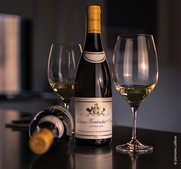 Eine elegante Fotografie, die eine Flasche Puligny-Montrachet Premier Cru des renommierten Domaine Leflaive in den Mittelpunkt rückt und durch ein sanftes Licht veredelt wird.