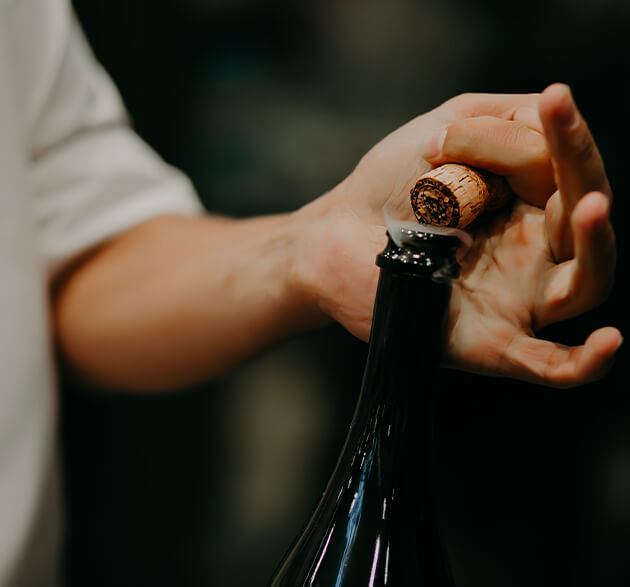 main débouchant une bouteille de vin 