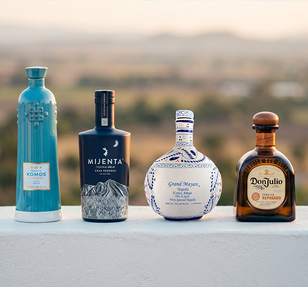 Une photographie mettant en scène quatre flacons de tequila de prestige, issus des maisons Don Julio, Grand Mayan, Komos et Mijenta.