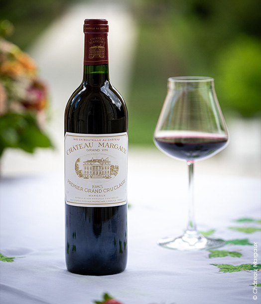 Château Margaux – Premier Grand Cru Classé (Margaux), millésime 1985, bouteille avec verre de vin rouge sur table