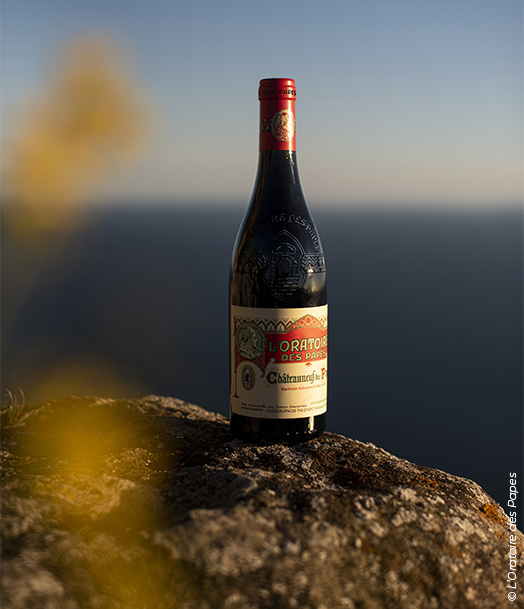 L’Oratoire des Papes – Châteauneuf-du-Pape, bouteille de vin rouge en extérieur avec horizon marin