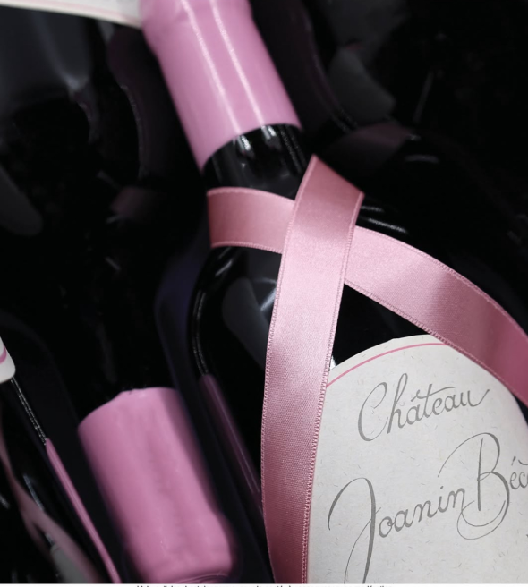 A bottle of Château Joanin Bécot lying down with a pink ribbon
