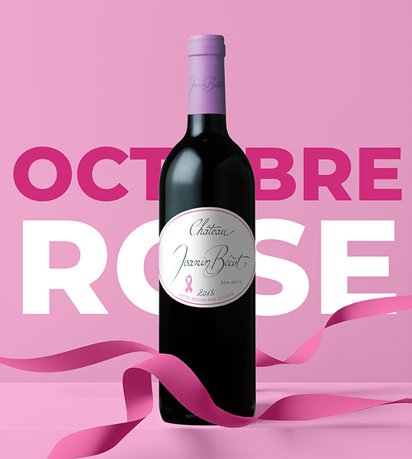 Une bouteille couchée de Château Joanin Bécot avec un ruban rose
